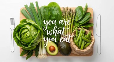 The text you are what you eat is displayed with fresh vegetables on a cutting board. The background is white. The image is a flat lay, top view.