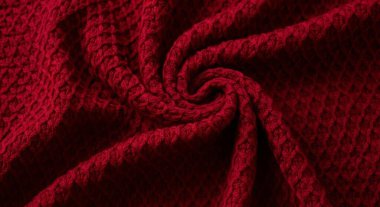 A close-up shot of red knitted fabric, showcasing a spiral pattern texture. Ideal for backgrounds, textile designs, and adding a warm, cozy touch to any project.