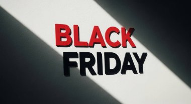 Beyaz bir duvara kırmızı ve siyah harflerle yazılmış koyu bir Kara Cuma tabelası, gölgeler. Tatil sezonunda reklam satışları ve tanıtımlar için ideal..