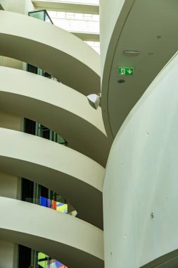 Beyaz duvarları, modern tasarım elementleri ve görünür acil çıkış işareti olan kıvrımlı mimari iç mekan..