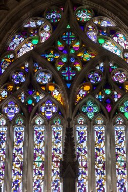 Gotik bir ortamda detaylı çiçek ve dini tasarımlar içeren renkli vitray..