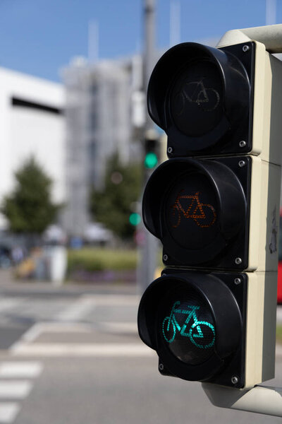 Зеленый велосипедный светофор ярко светит на оживленном городском перекрестке в солнечный день.