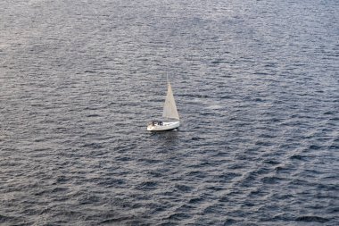Yalnız bir yelkenli engin bir okyanusta sürüklenir, yukarıdan gelen yumuşak ışıkta yakalanır..