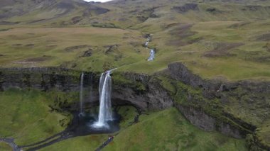 İzlanda insansız hava aracı görüntüsü. Seljalandsfoss şelalesi. Bir yamaçtan uzakta bir şelale görülüyor.