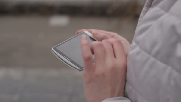 Las manos de chica sostienen el teléfono inteligente en la ciudad — Vídeo de stock