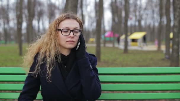 Jeune femme parlant au téléphone à l'extérieur dans un parc — Video