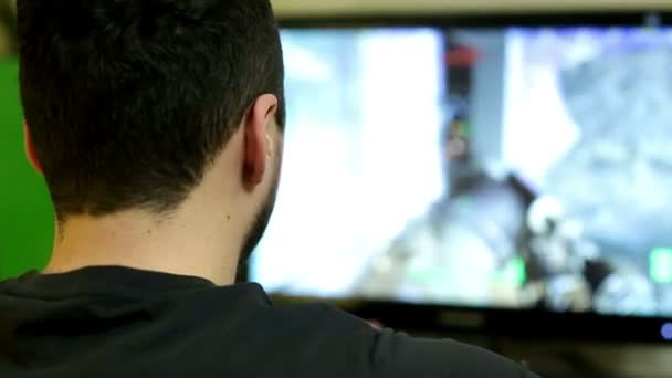 Νεαρός άνδρας παίζει ένα παιχνίδι βίντεο στον προσωπικό υπολογιστή — Αρχείο Βίντεο