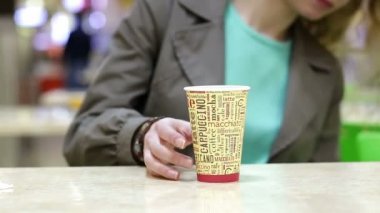 Kahve veya çay içme ve cep telefonuyla bir kafede mutlu genç kadın