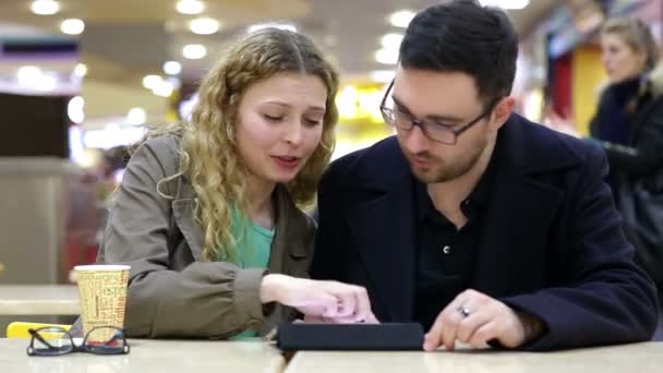 Jong paar zijn met behulp van Tablet Pc in de coffeeshop — Stockvideo