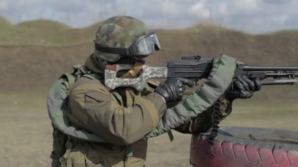 Een soldaat met een machinegeweer op een militaire schietbaan schieten op een doel. — Stockvideo