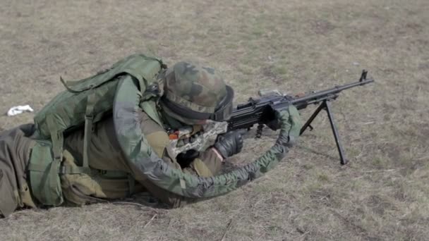 Un soldat avec une mitrailleuse sur un champ de tir militaire tirant sur une cible . — Video