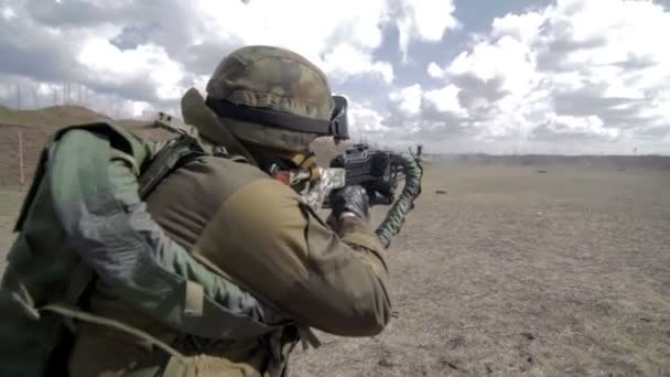 Um soldado com uma metralhadora num campo de tiro militar a disparar contra um alvo. . — Vídeo de Stock