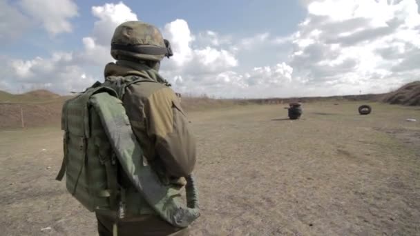 Een soldaat met een machinegeweer op een militaire schietbaan schieten op een doel. — Stockvideo