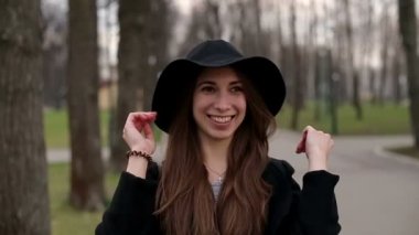 Genç güzel kız siyah şapkalı gülümseyerek mutlu bir şekilde kameraya, ağır çekim, kapatın.