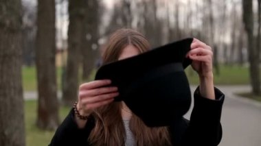 Genç güzel kız siyah şapkalı gülümseyerek mutlu bir şekilde kameraya, ağır çekim, kapatın.