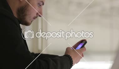 Kapalı köprüde bir akıllı telefon ile genç adam.