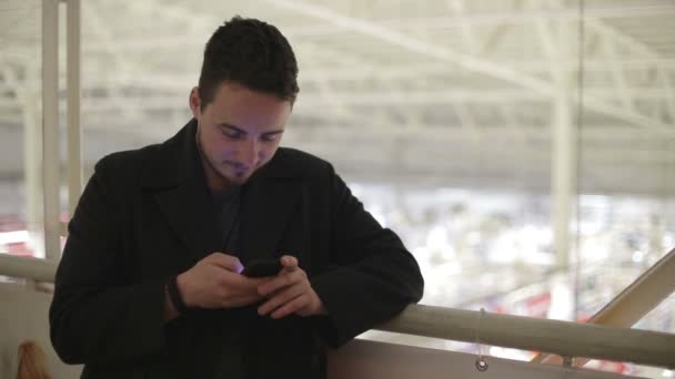 Jonge man met een smartphone op de overdekte brug. — Stockvideo