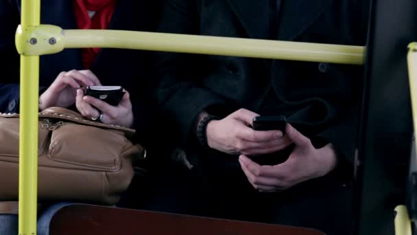 Casal jovem sentar juntos em um ônibus e usar smartphones — Vídeo de Stock