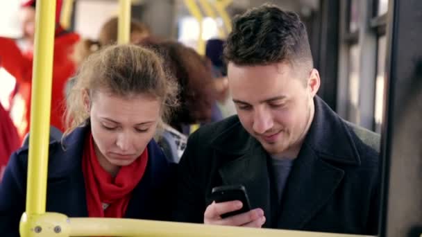 Young couple sit together on a bus and use smartphones — Stock Video