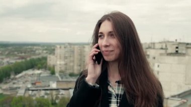 Genç kadın bir smartphone çatıda kullanır.