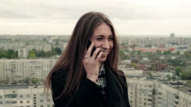 Genç kadın bir smartphone çatıda kullanır.