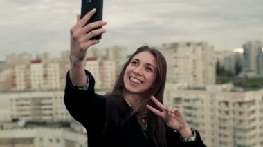 Genç kadın bir smartphone çatıda kullanır.