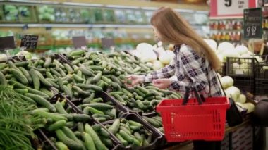 Genç kadın ürünleri süpermarkette seçer.