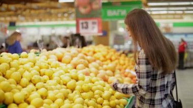 Genç kadın ürünleri süpermarkette seçer.