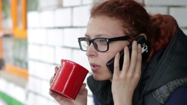 Schöne Frau trinkt Kaffee und telefoniert — Stockvideo