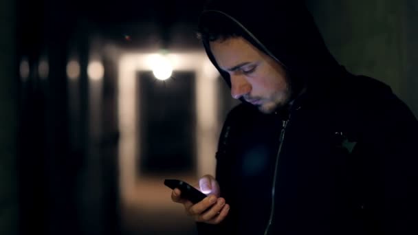Hombre en pasillo oscuro con teléfono — Vídeo de stock