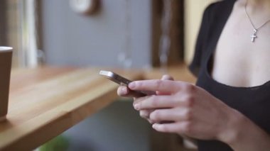 Genç kadın kapalı kentsel kafede oturan onun smartphone içme kahve ve kullanım