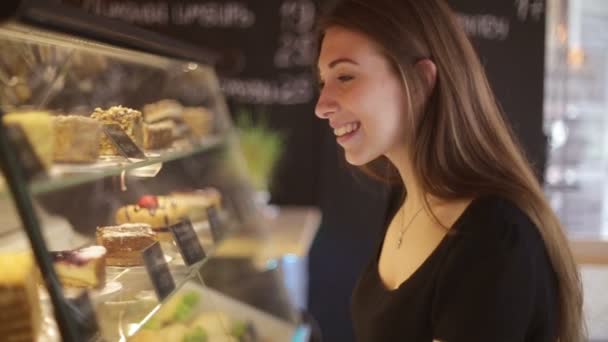 Vackra kvinnliga kunden shopping showcase i en bageri butik pekar på efterrätten hon köper — Stockvideo