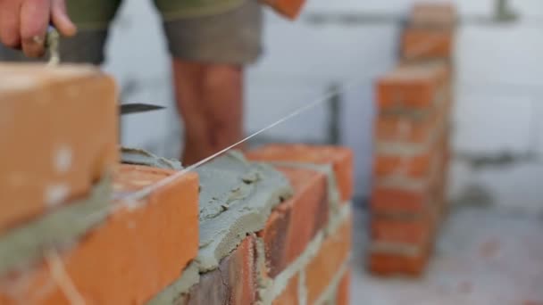 Работа кладет кирпич на строительную площадку — стоковое видео