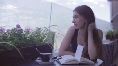Sokak kafede oturan ve notları not defterinde yazılı güzel kız