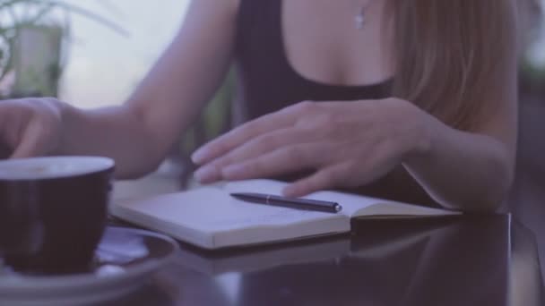 Menina bonita sentada no café de rua e escrevendo notas no caderno — Vídeo de Stock