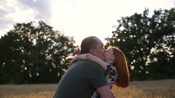 Rallentatore di giovane coppia sul campo al tramonto, uomo girando donna rotonda — Video Stock