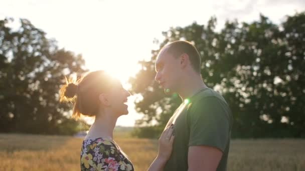 A couple hug, kiss and then walk in a wide open golden field at sunset — Stock Video