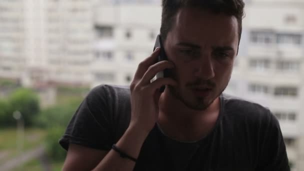 Mladý muž mluví na mobilním telefonu a rozhlédl se kolem sebe — Stock video