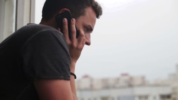 Giovane uomo che parla al cellulare e si guarda intorno — Video Stock