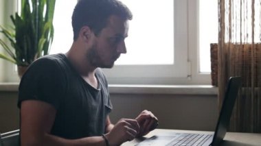 Genç adam evde mutfak dizüstü kullanarak kredi kartıyla alışveriş