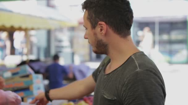 El hombre compra duraznos en un mercado de verduras en el día — Vídeo de stock