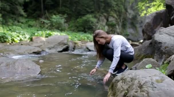 Jonge vrouw, wassen van haar handen in de rivier van de berg — Stockvideo