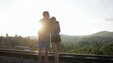 Yürüyüş ve huging birlikte dağlarda eski demiryolu üzerinde genç Çift