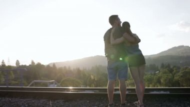 Yürüyüş ve huging birlikte dağlarda eski demiryolu üzerinde genç Çift