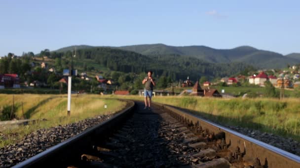 Человек ходит по железной дороге в горах — стоковое видео