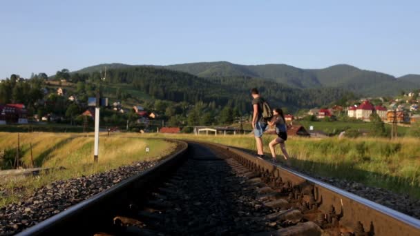 Молодая пара, идущая вместе по старой железной дороге в горах — стоковое видео