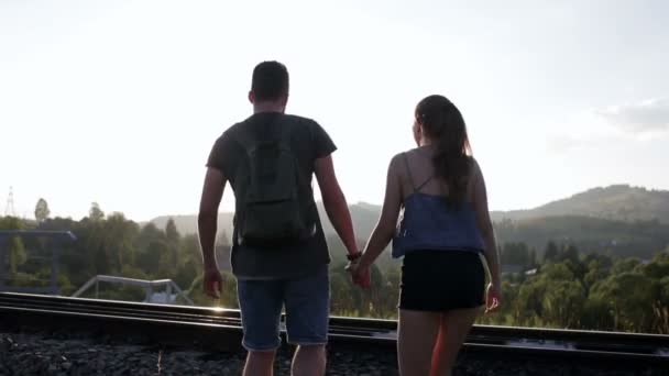 Pasangan muda berjalan dan berpelukan bersama di rel kereta api tua di pegunungan — Stok Video