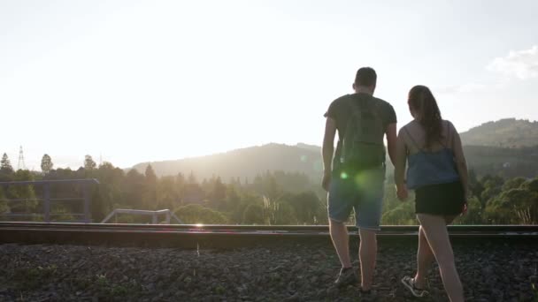 Junges Paar spaziert und umarmt gemeinsam auf alter Eisenbahn in den Bergen — Stockvideo
