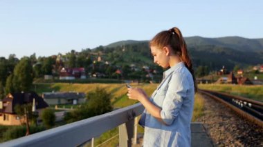 Gülümseyen güzel genç kadın ile smartphone dağlarda