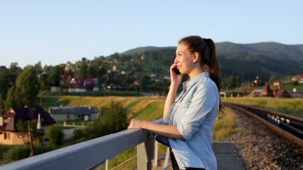 Lächelnde schöne junge Frau mit Smartphone in den Bergen — Stockvideo